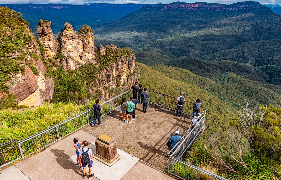 People at Echo Point lookout viewing the Three Sisters rock formation in Blue Mountains, Australia.