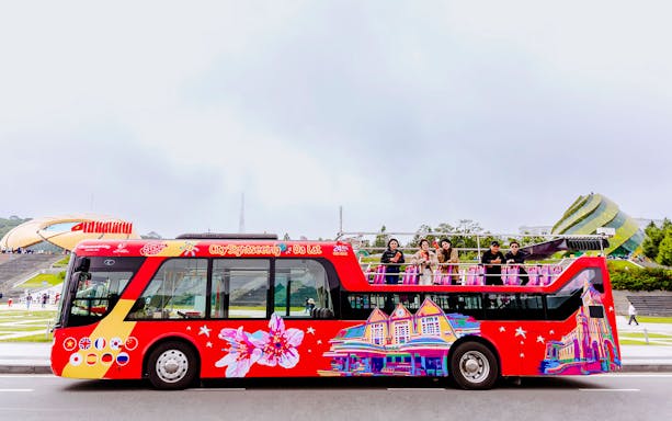 Hop on Hop off bus near National Convention Center, Da Lat with tourists on top deck.