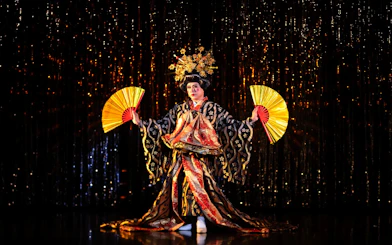 Performer in traditional costume with fans at Calypso Cabaret, Bangkok.