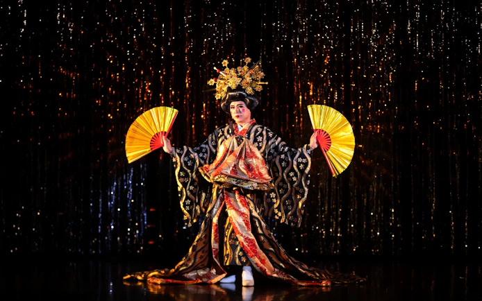 Performer in traditional costume with fans at Calypso Cabaret, Bangkok.