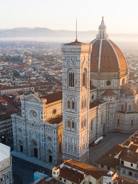 Florence Duomo aerial view with surrounding cityscape at sunrise.