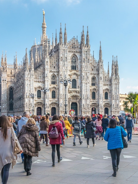 Tourists on Milan Hop-On Hop-Off bus tour with Milan Duomo in view.
