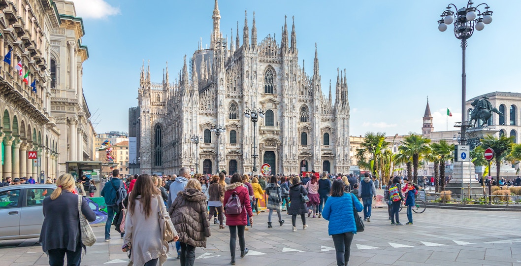Tourists on Milan Hop-On Hop-Off bus tour with Milan Duomo in view.