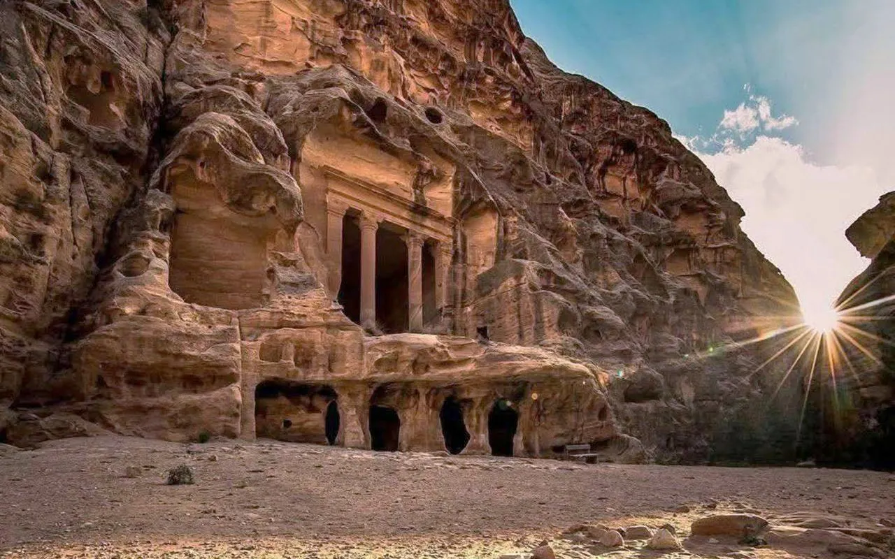 Ancient rock-carved facade in Petra, Jordan, with sunlight streaming through.