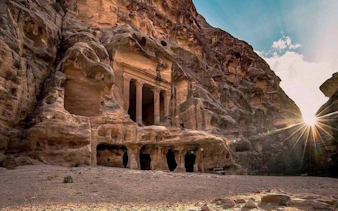 Ancient rock-carved facade in Petra, Jordan, with sunlight streaming through.