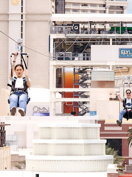 People ziplining on Fly LINQ Zipline with Las Vegas skyline in the background.