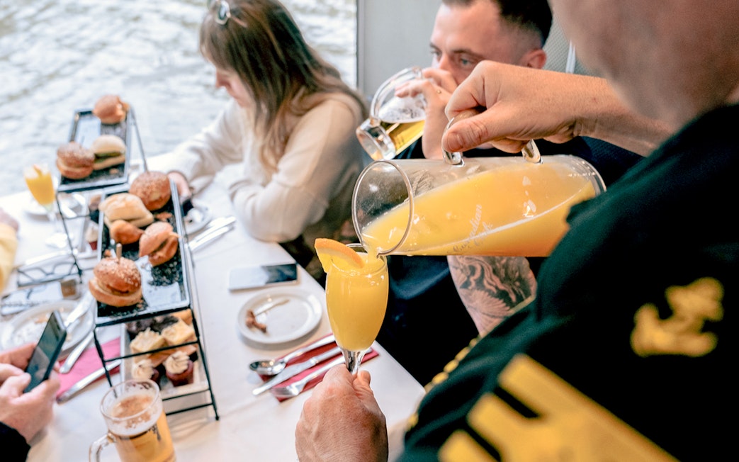 Pouring orange juice into a glass on a brunch cruise in Melbourne.