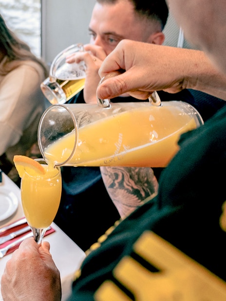 Pouring orange juice into a glass on a brunch cruise in Melbourne.