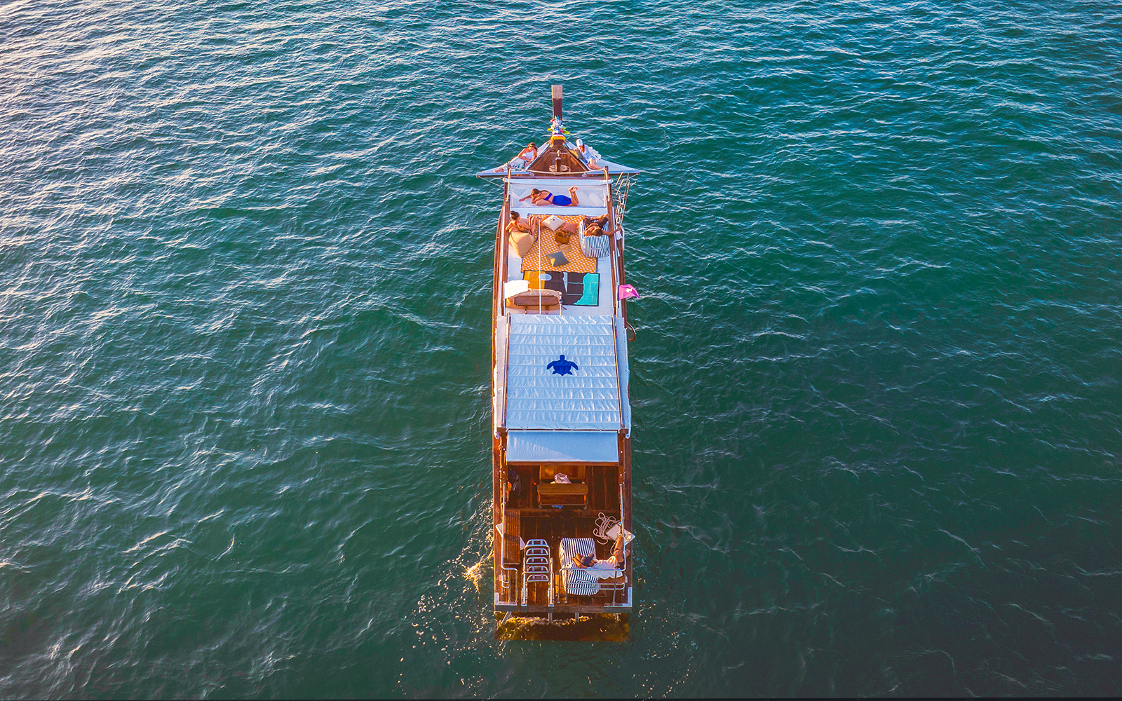 Longtail boat cruise at sunset in Krabi with people relaxing on deck.