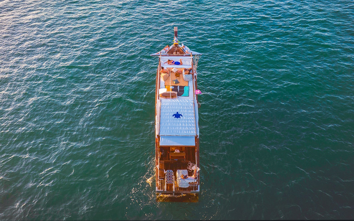 Longtail boat cruise at sunset in Krabi with people relaxing on deck.