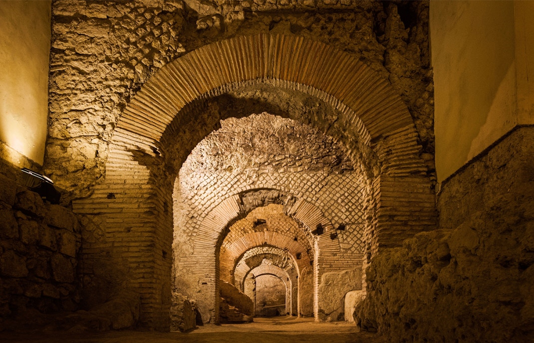 Naples Underground tour entrance with ancient stone arches and dimly lit passageways in Napoli Sotterranea.