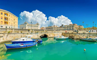 Boats docked at Ortigia Island with historic buildings in the background.