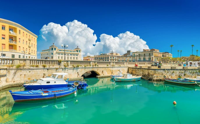 Boats docked at Ortigia Island with historic buildings in the background.