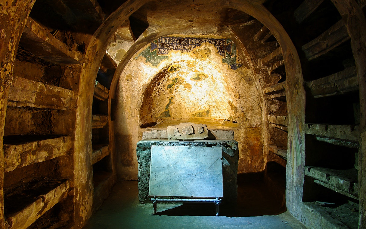 Exploring the Catacombs of San Gaudioso in Naples with ancient tombs and inscriptions.