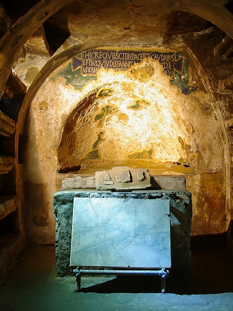 Exploring the Catacombs of San Gaudioso in Naples with ancient tombs and inscriptions.