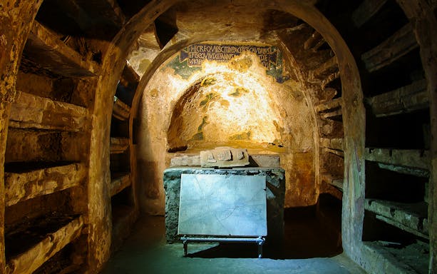 Exploring the Catacombs of San Gaudioso in Naples with ancient tombs and inscriptions.