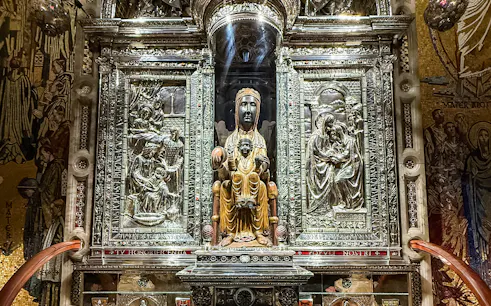 Black Madonna statue at Montserrat Monastery, Spain, surrounded by ornate carvings.