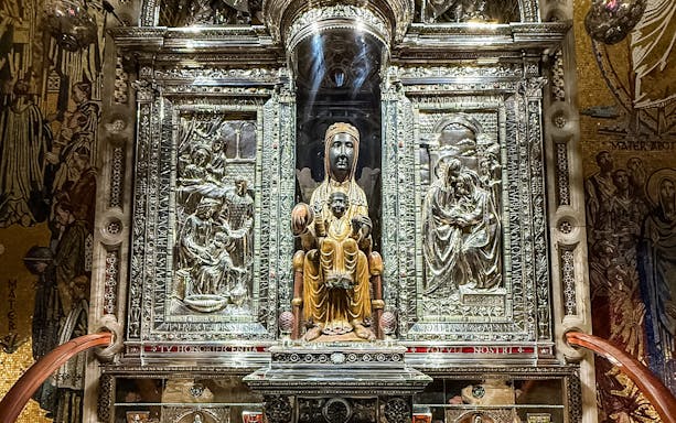 Black Madonna statue at Montserrat Monastery, Spain, surrounded by ornate carvings.
