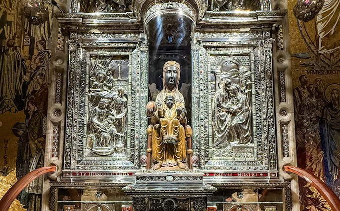 Black Madonna statue at Montserrat Monastery, Spain, surrounded by ornate carvings.
