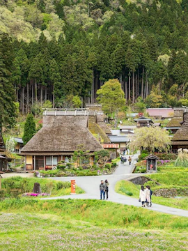 Traditional thatched-roof houses in Miyama Village, Kyoto, surrounded by lush greenery.