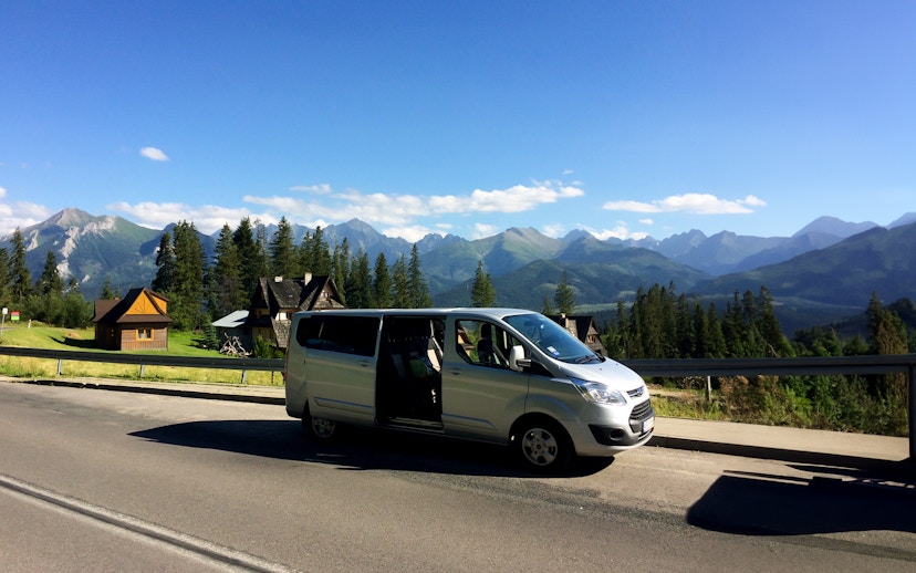 Minivan parked on a road with Tatra Mountains in the background near Zakopane, Poland.