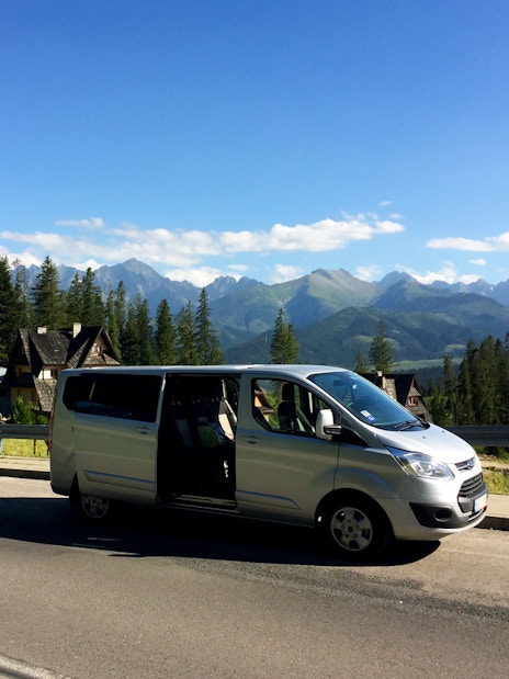 Minivan parked on a road with Tatra Mountains in the background near Zakopane, Poland.