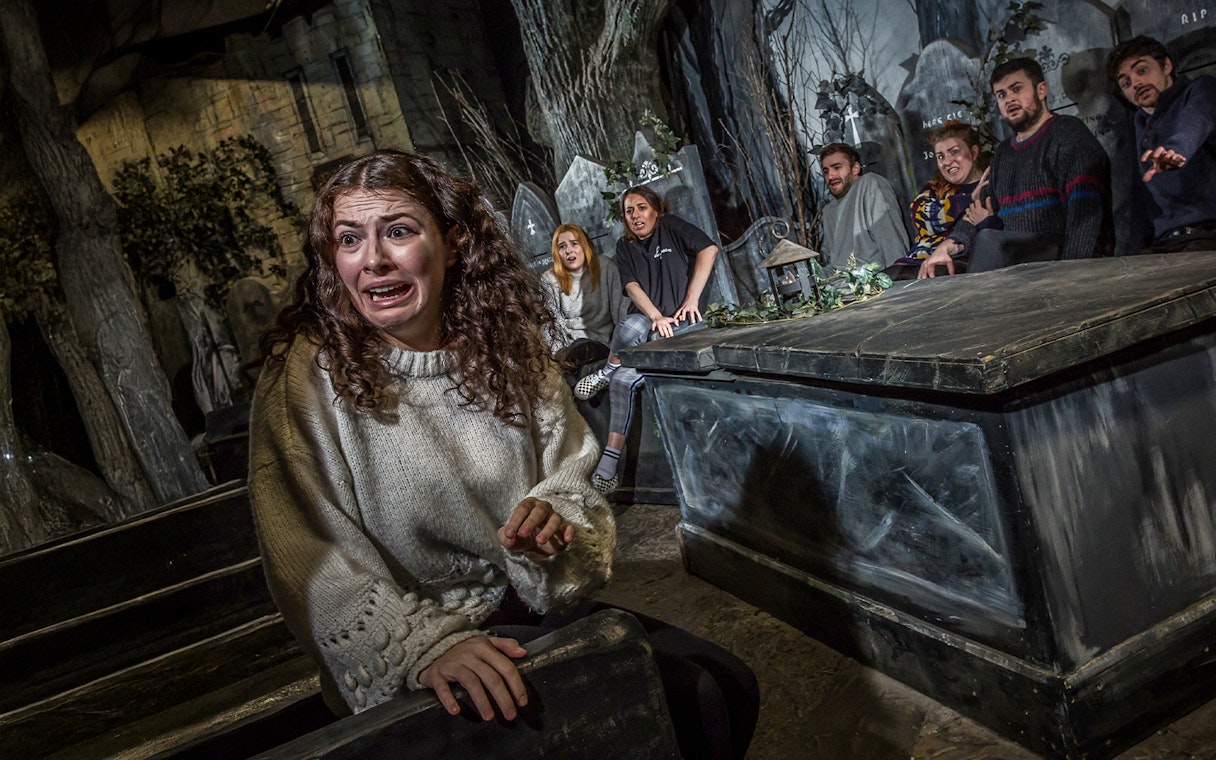 Group experiencing a ghost tour at Greyfriar's Kirkyard, Edinburgh, with expressions of fear.