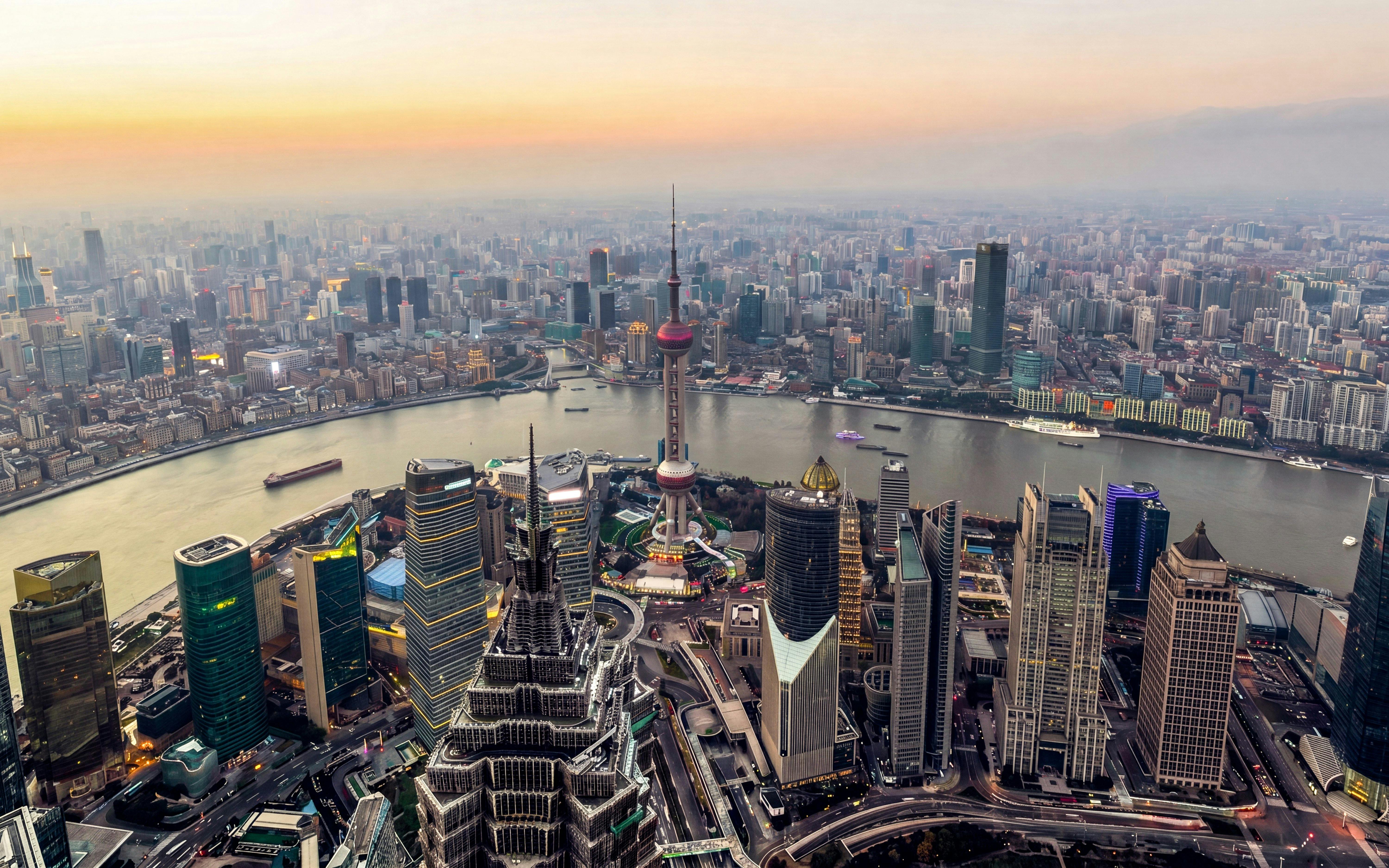 Shanghai skyline at sunset with Oriental Pearl Tower and Huangpu River.