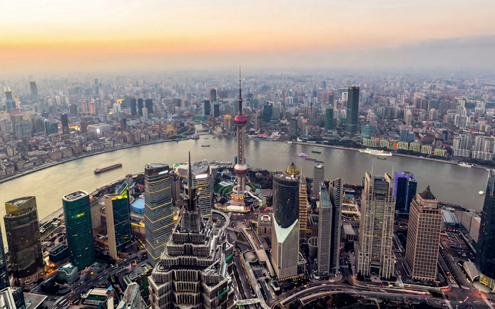 Shanghai skyline at sunset with Oriental Pearl Tower and Huangpu River.