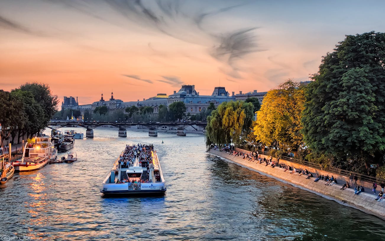 Evening cruise on the Seine River with sunset view and Parisian landmarks.