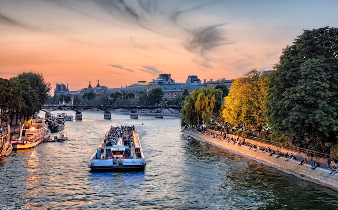 Evening cruise on the Seine River with sunset view and Parisian landmarks.