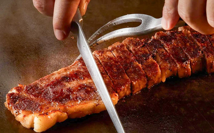 Slicing grilled steak on Okura Cruise Bangkok.
