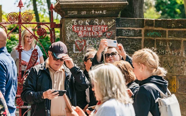 Tourists photographing Strawberry Field gate in Liverpool.