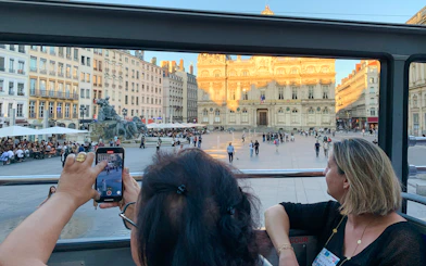 Open-top bus view of Lyon's Place des Terreaux and Bartholdi Fountain, France.