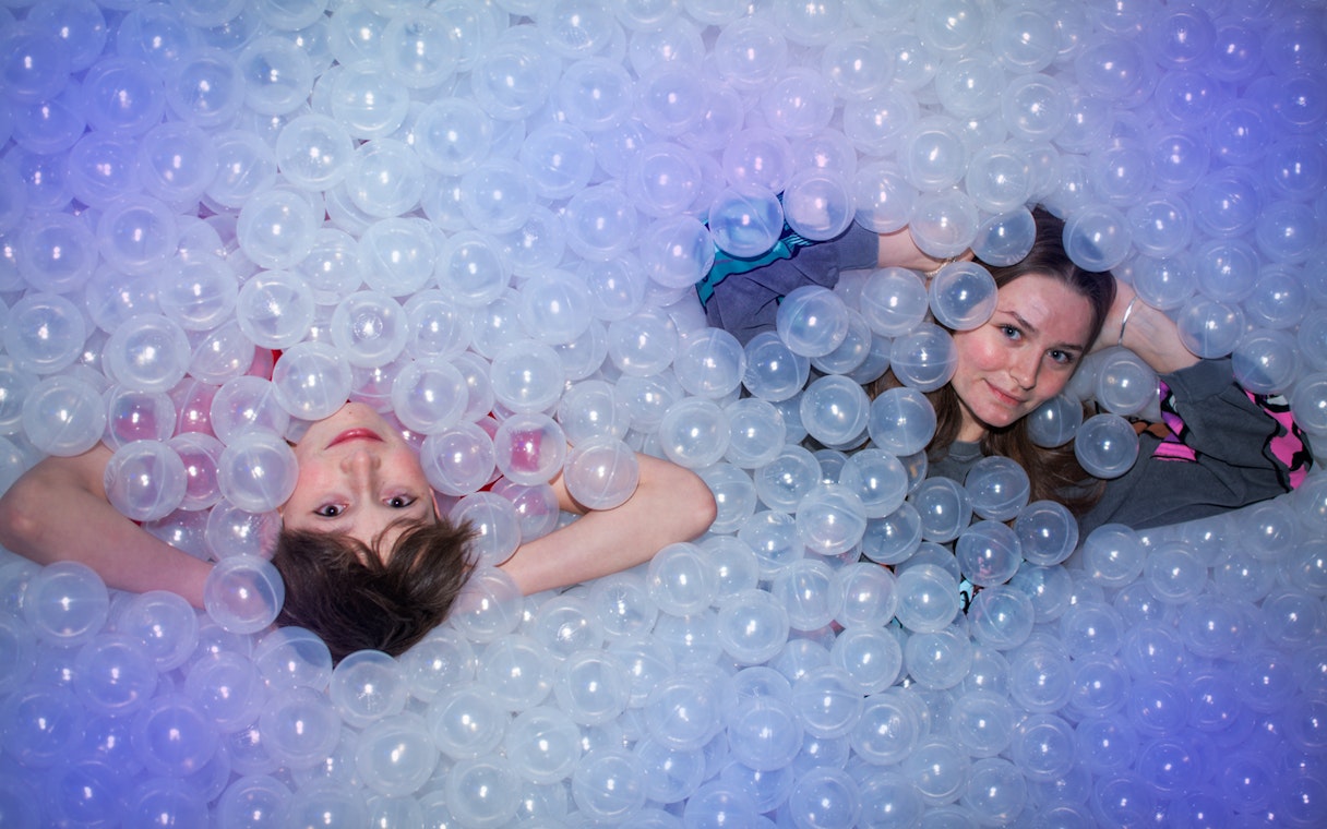 People lying in a ball pit at The TUBE attraction.