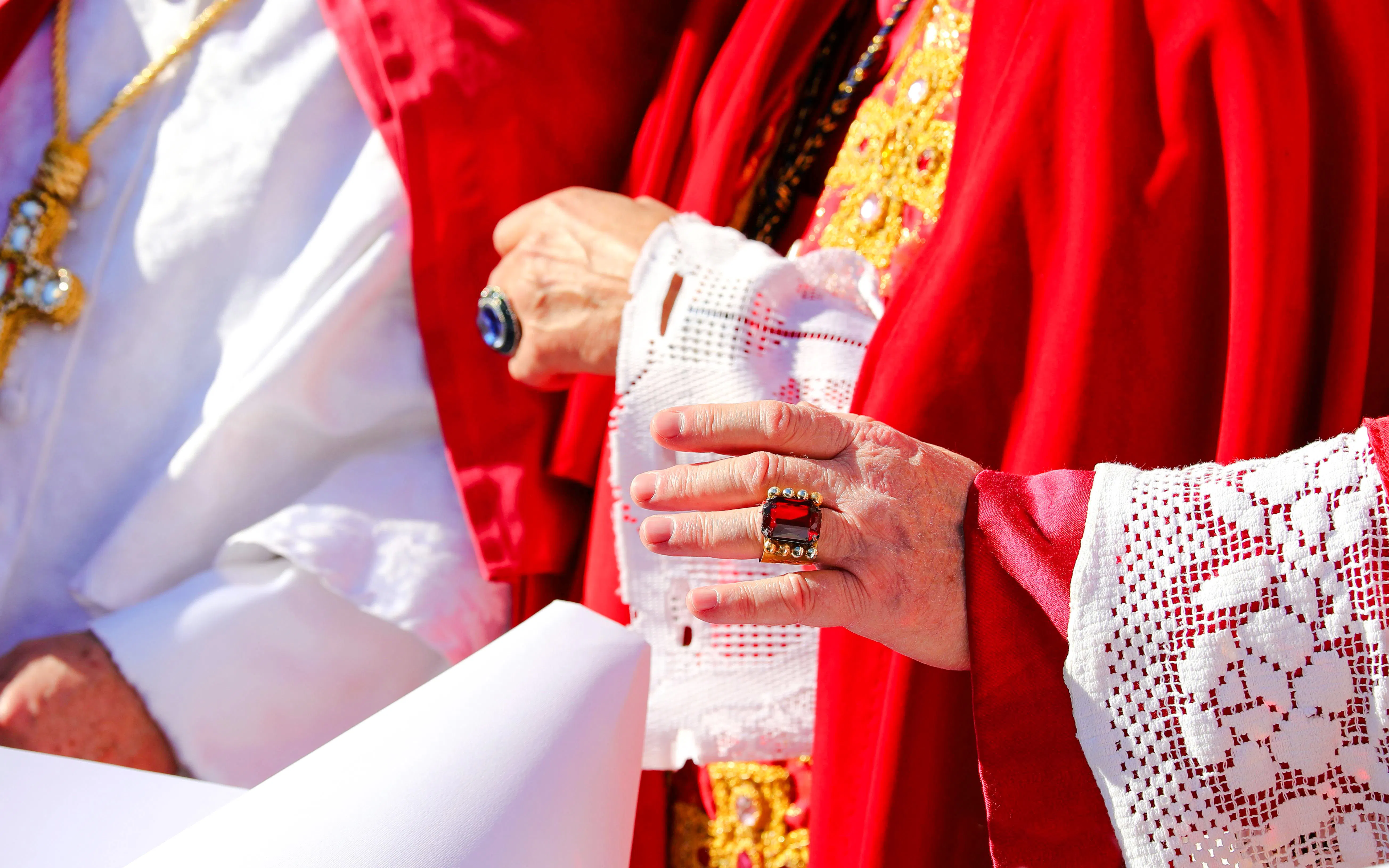 Clergy in red and white vestments holding a scroll during Christmas Day Mass.