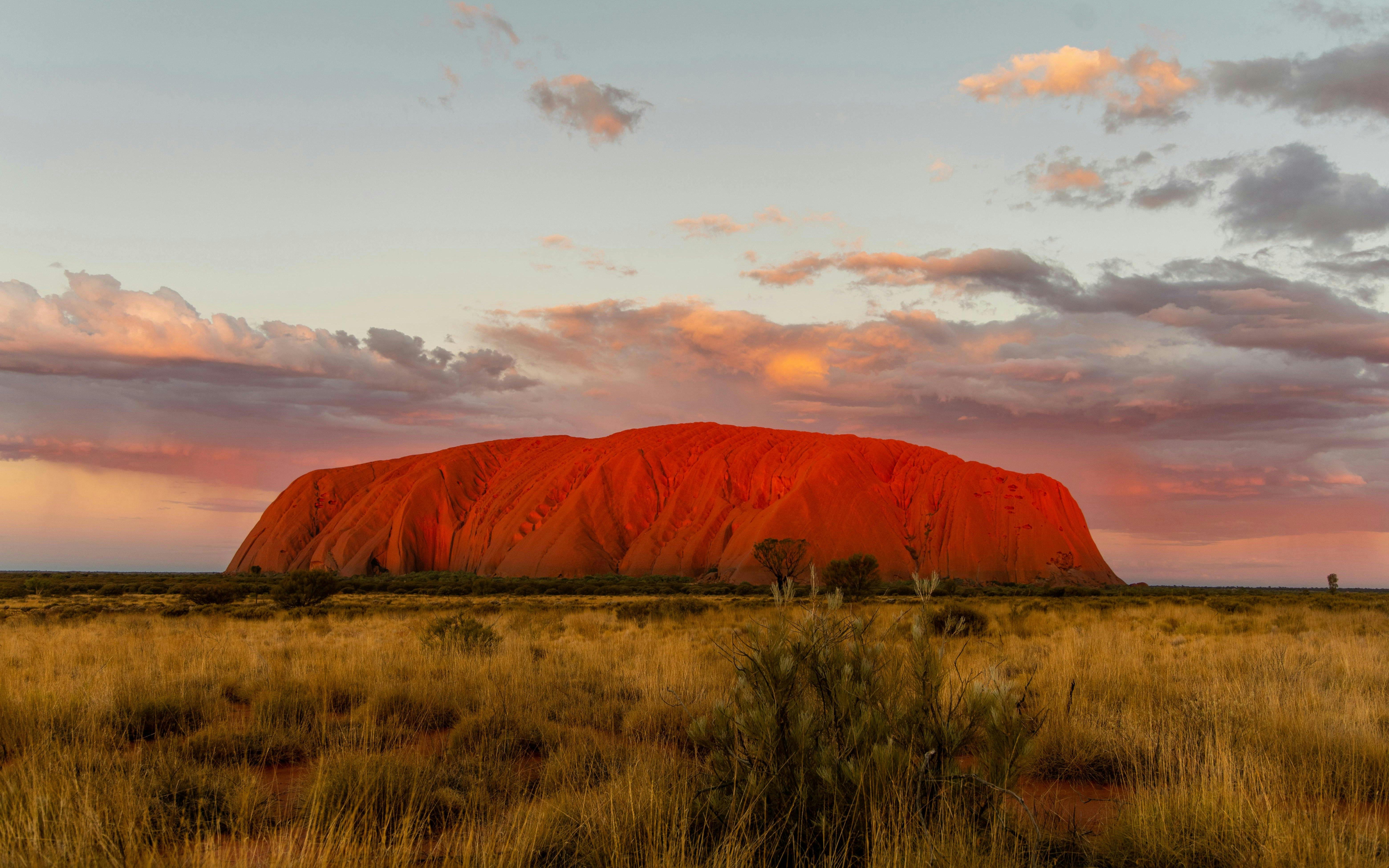 Uluru at sunset with vibrant sky, part of the Sacred Sites Guided Tour in Australia.