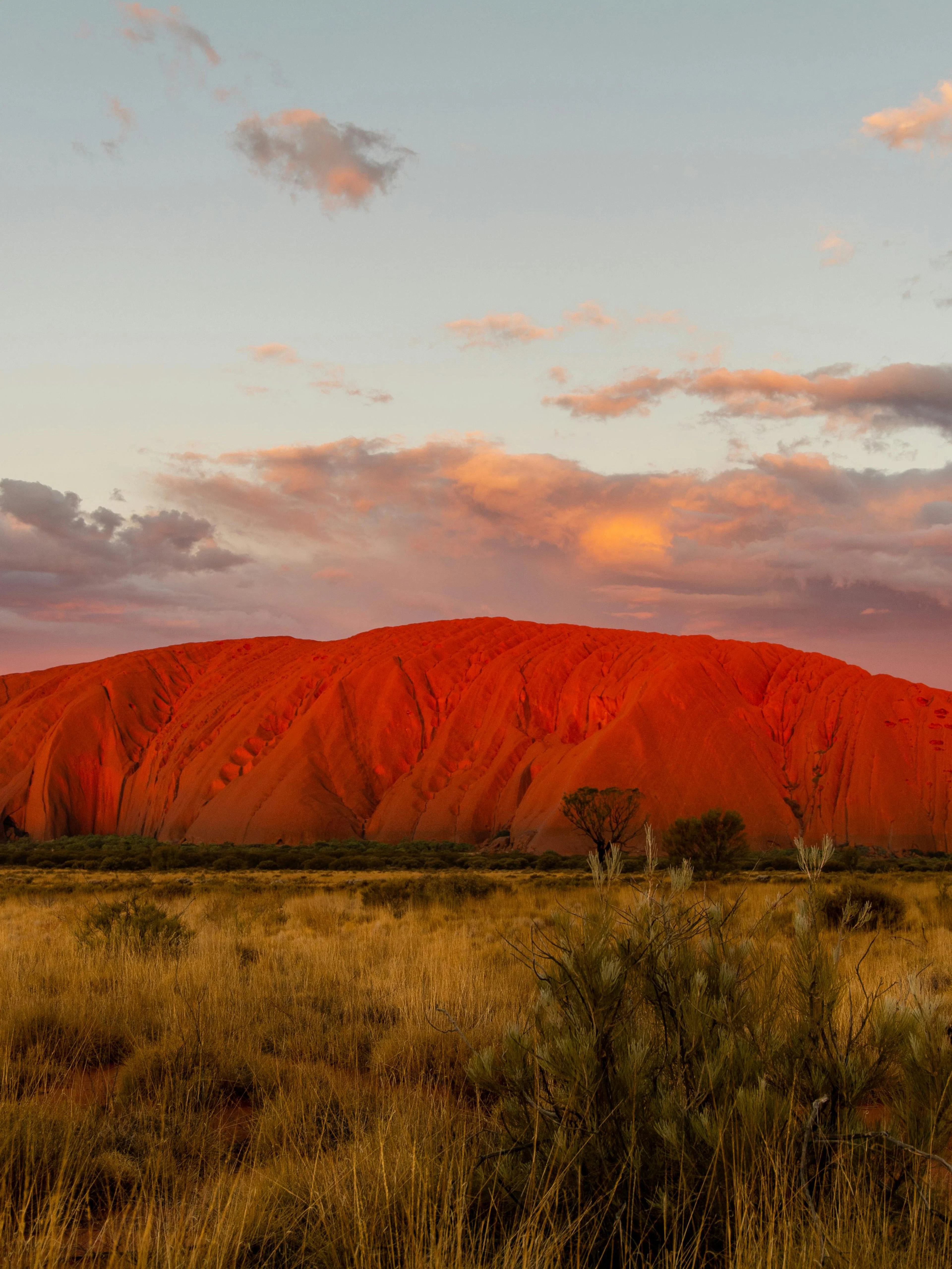 Uluru at sunset with vibrant sky, part of the Sacred Sites Guided Tour in Australia.