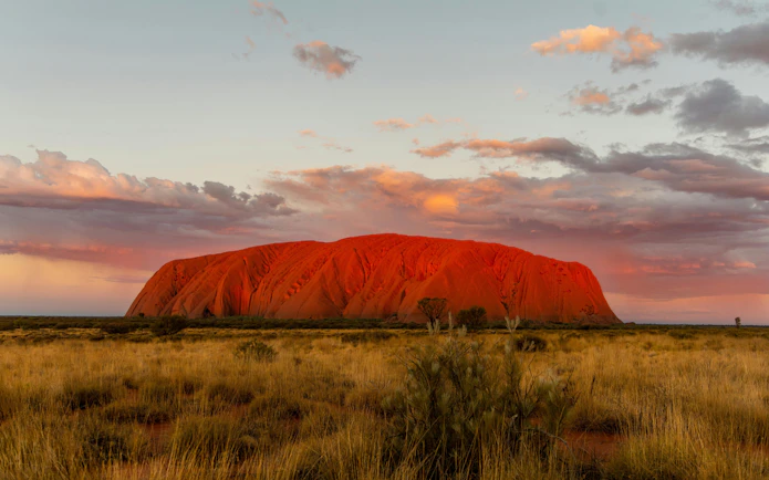 Uluru at sunset with vibrant sky, part of the Sacred Sites Guided Tour in Australia.