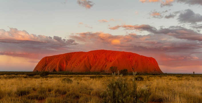Uluru at sunset with vibrant sky, part of the Sacred Sites Guided Tour in Australia.