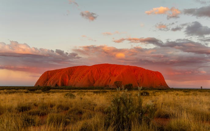 Uluru at sunset with vibrant sky, part of the Sacred Sites Guided Tour in Australia.