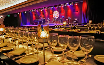 Dining setup at Michelangelo Tango Show with stage and lighting in Buenos Aires.