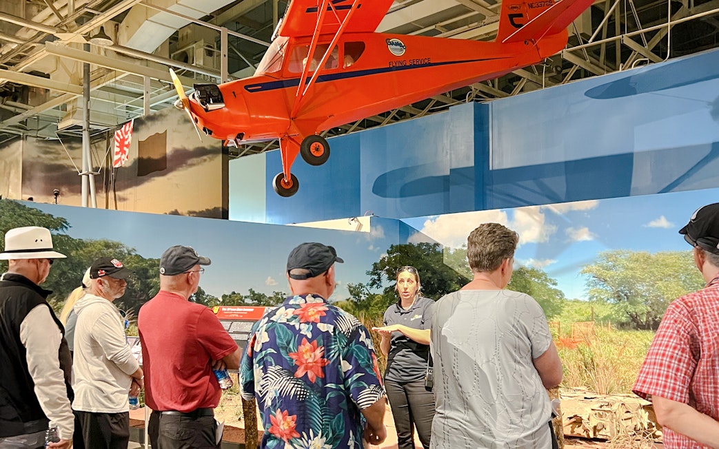 Guide explaining exhibit to visitors at Pearl Harbor Aviation Museum.