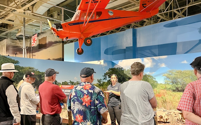 Guide explaining exhibit to visitors at Pearl Harbor Aviation Museum.