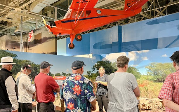 Guide explaining exhibit to visitors at Pearl Harbor Aviation Museum.