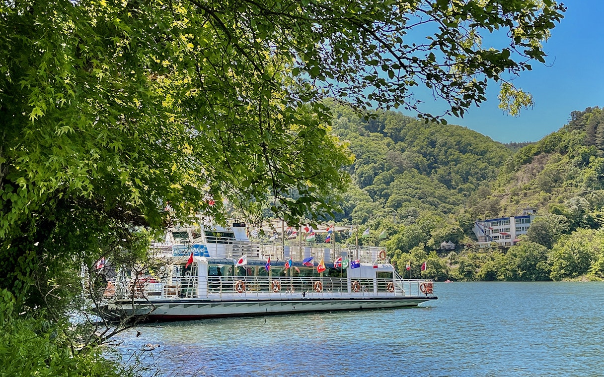 Ferry on the water surrounded by trees and hills in Nami Island, South Korea.