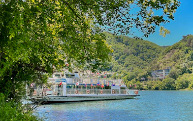 Ferry on the water surrounded by trees and hills in Nami Island, South Korea.