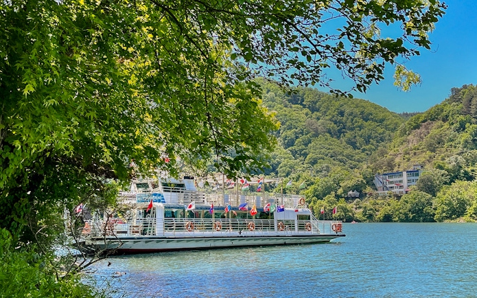 Ferry on the water surrounded by trees and hills in Nami Island, South Korea.