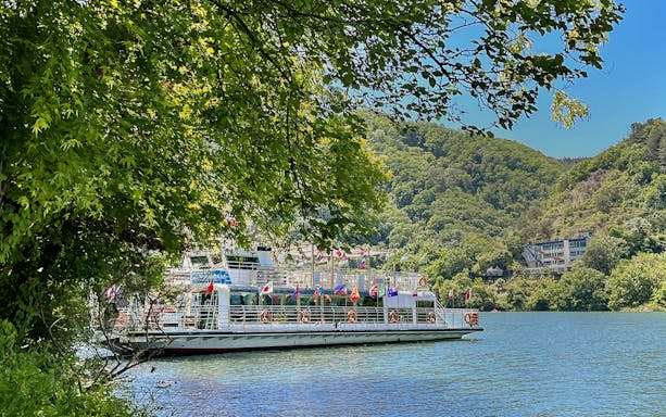 Ferry on the water surrounded by trees and hills in Nami Island, South Korea.
