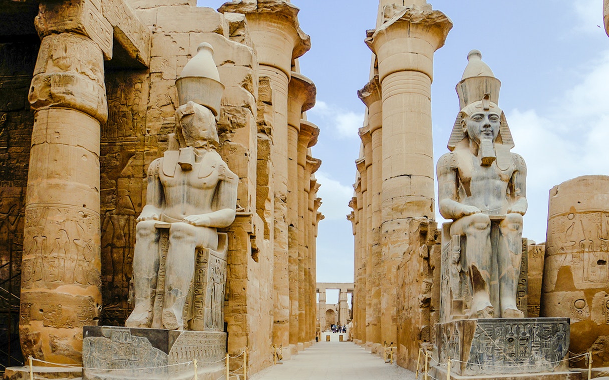 Giant statues at Karnak Temple in Luxor, Egypt, flanked by ancient columns.